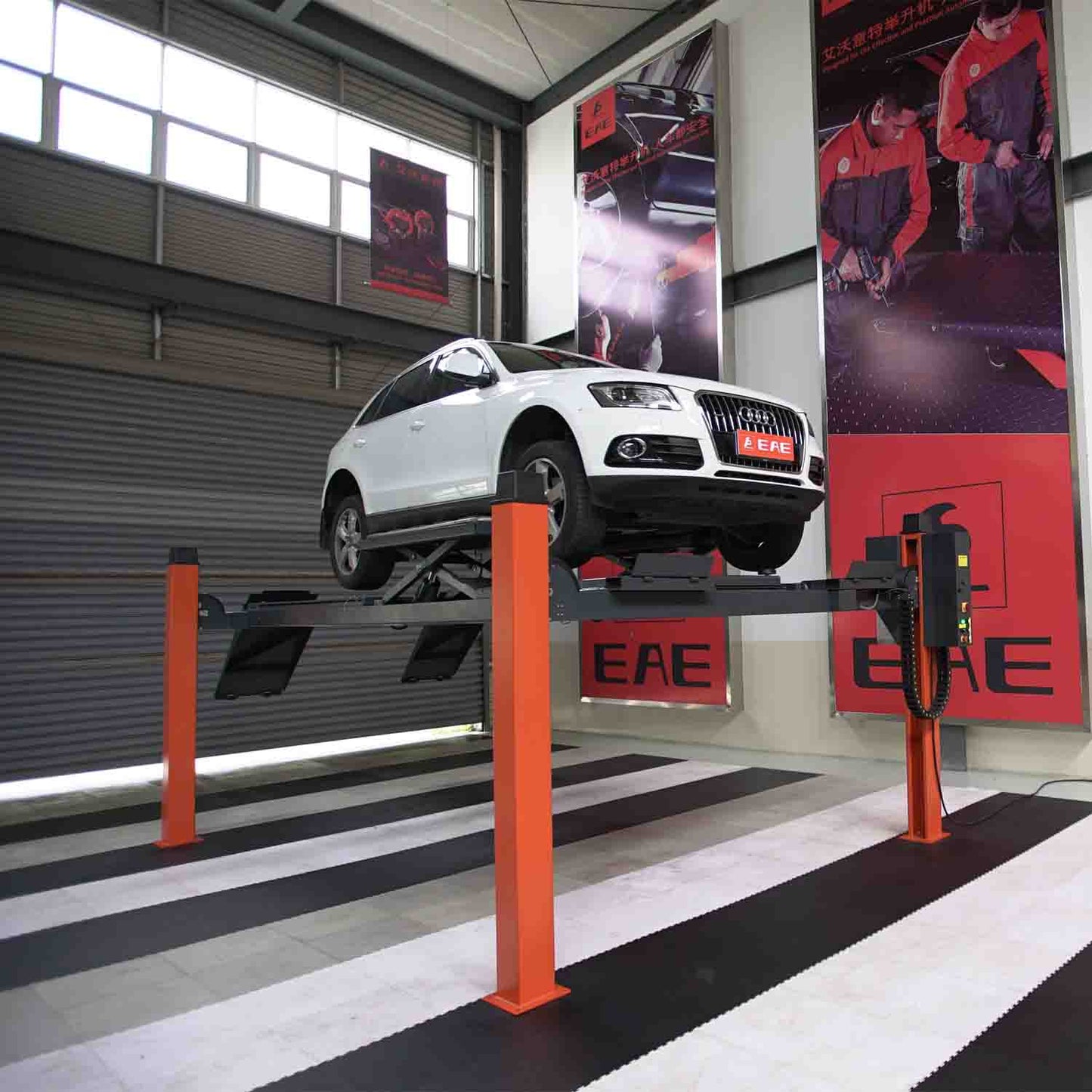 White SUV elevated on a four-post car hoist with orange columns, demonstrating vehicle alignment and servicing in an indoor automotive workshop, featuring EAE branding on the walls. - 4 Post Wheel Alignment Hoist - 4 Ton | EE-6435V2.B.48L.40T