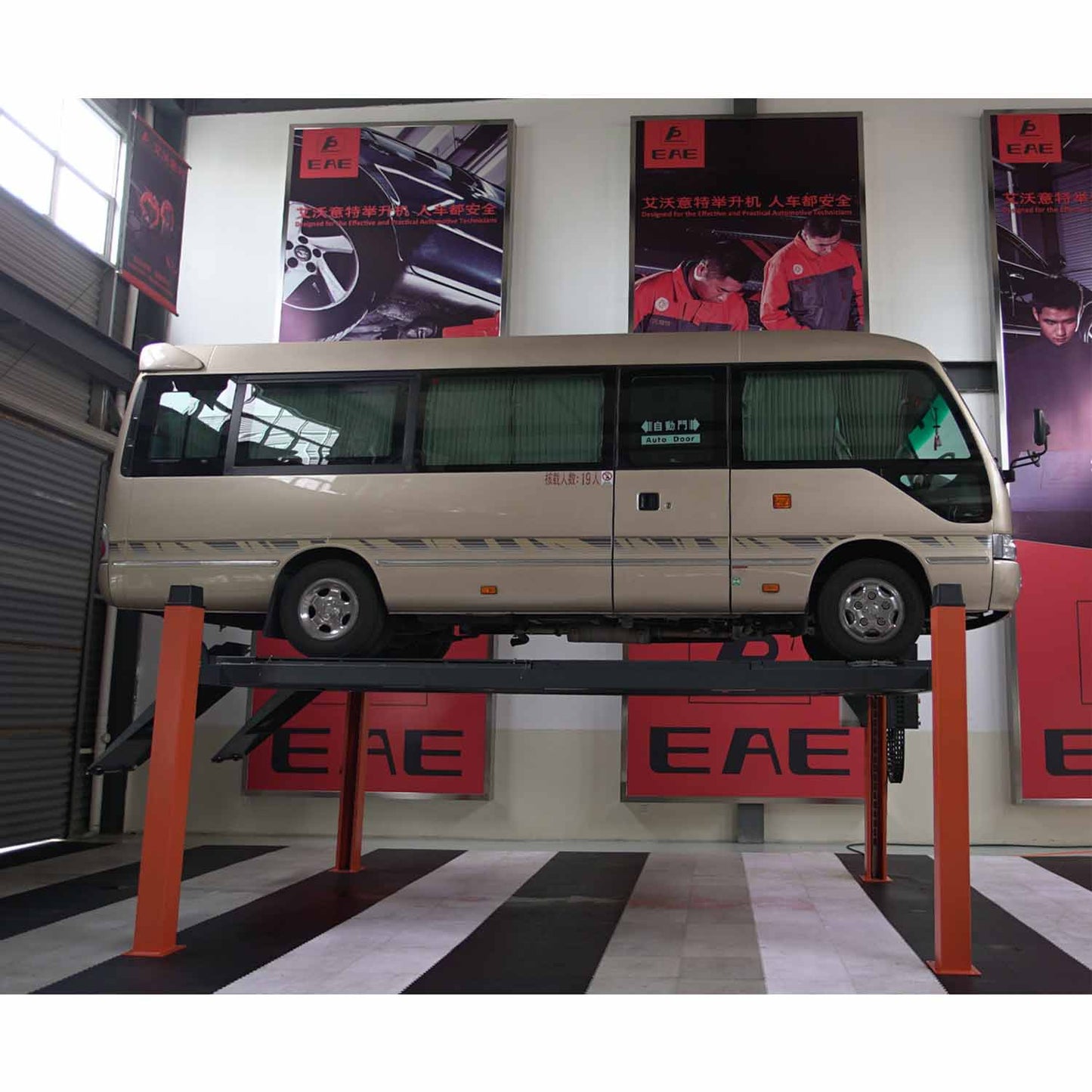 Minibus elevated on a four-post car hoist with orange columns inside a professional automotive workshop featuring EAE branding. - 4 Post Wheel Alignment Hoist - 4 Ton | EE-6435V2.B.48L.40T