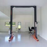Two-post automotive lift in a clean, well-lit workshop with windows, a desk, and office furniture in the background. - 2 Post Clear Floor Hoist - 4.5 Ton | EE-C10V2