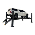 White SUV lifted on a four-post car hoist with drive-on ramps in an industrial garage, ready for maintenance and inspection. - 4 Post Workshop Hoist - 6 Ton | TL6.0PH