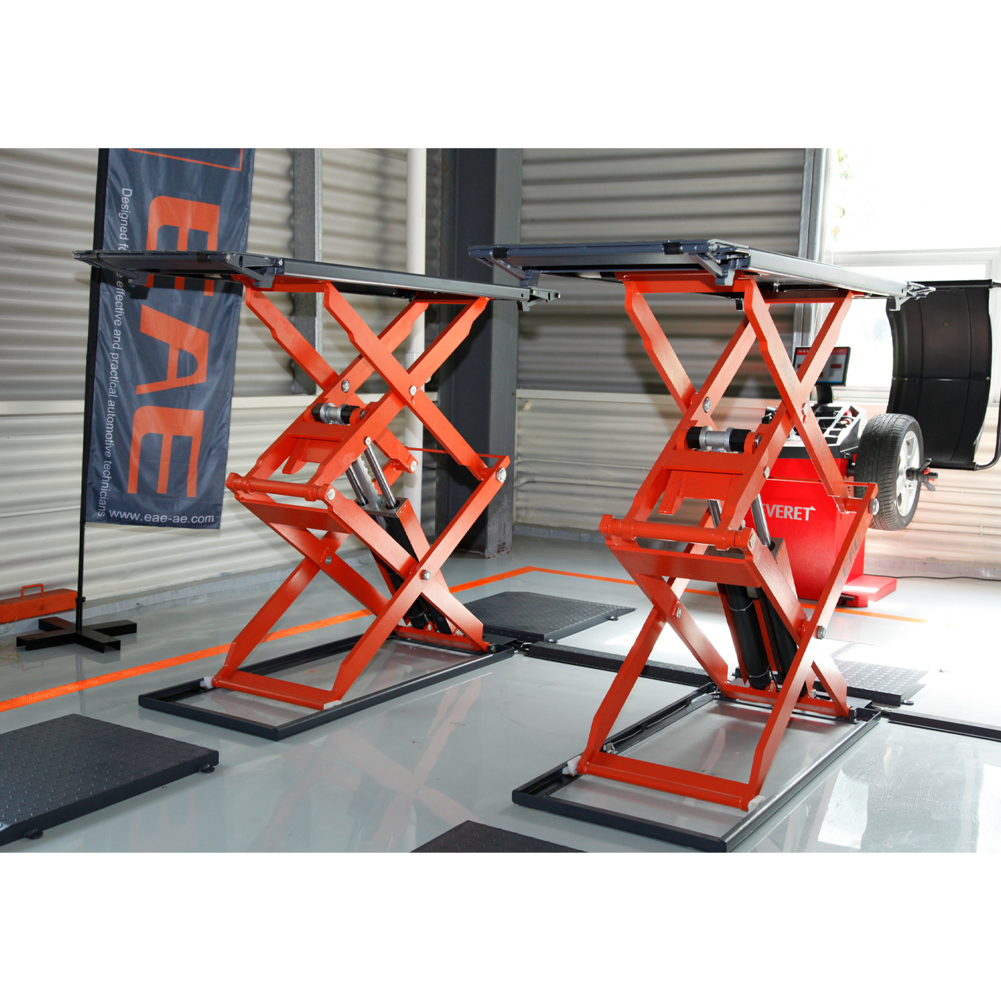 An orange scissor lifts in a workshop, positioned for vehicle maintenance.