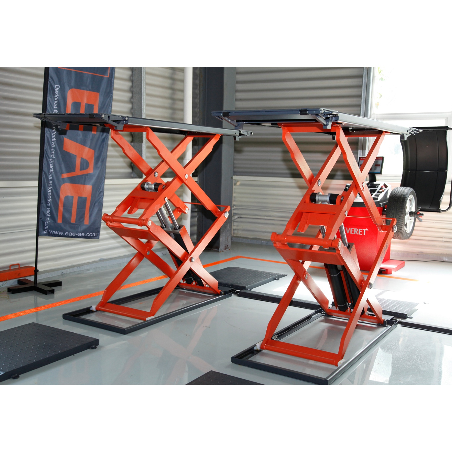 An orange scissor lifts in a workshop, positioned for vehicle maintenance.