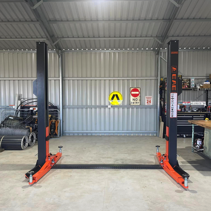 An empty Tufflift 2 post baseplate car hoist ready for use in a spacious industrial garage. - 2 Post Baseplate Hoist - 4 Ton | EE-F9