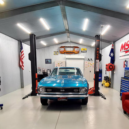 A blue classic car on a Tufflift 2 post baseplate car hoist in a tidy shed garage. - 2 Post Baseplate Hoist - 4 Ton | EE-F9