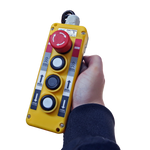 Handheld control panel with buttons and an emergency stop for operating a lift, showcasing user-friendly and safe controls for lifting equipment.