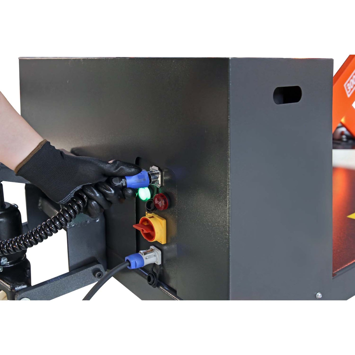 Gloved hand connecting a cable to a control panel on a lift, illustrating the setup and power connections for operating heavy-duty lifting equipment.