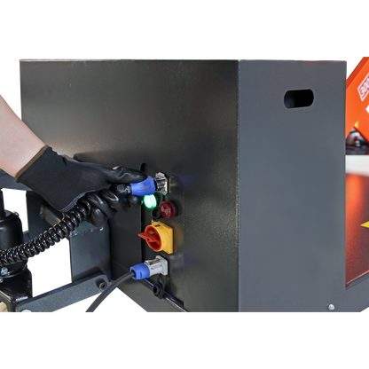 Gloved hand connecting a cable to a control panel on a lift, illustrating the setup and power connections for operating heavy-duty lifting equipment.