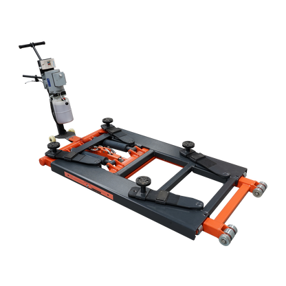 An orange and black EAE hydraulic scissor lift, model TS6600, in a fully lowered position on a workshop floor. The control unit with wiring is connected to the lift, showcasing its compact design. 