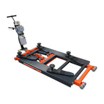 An orange and black EAE hydraulic scissor lift, model TS6600, in a fully lowered position on a workshop floor. The control unit with wiring is connected to the lift, showcasing its compact design. 
