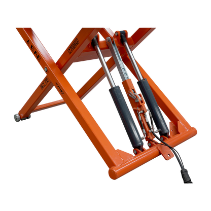 A close-up view of the hydraulic cylinders and mechanisms of an orange EAE scissor lift, model TS6600. The lift's support structure, labeled with a 2700kg capacity, is visible along with connected hydraulic lines and pistons.