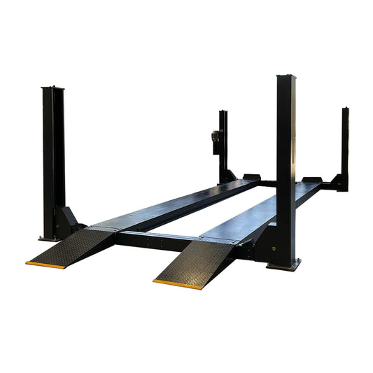 A heavy-duty 12,000 kg capacity commercial vehicle hoist inside a well-lit industrial workshop, featuring a dark grey 4 post truck hoist with yellow-edged ramps, pneumatic single point lock release, and workers actively engaged around the site. - 4 Post 7.5M Long Truck Hoist – 12 Ton | TL12.0TH-7.5