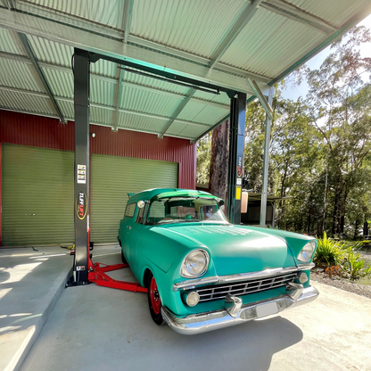 A vibrant, mint green vintage car parked in between a Tufflift 2 post car hoist - 2 Post Clear Floor Hoist - 4 Ton | TL4.0OHDI