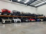 Indoor automotive storage facility with two levels of cars on four-post car lifts, showcasing various vehicles neatly parked in a spacious and well-organized environment. - 4 Post Twin Platform Parking Hoist – 4 Ton | TLD4.0TPL5.0M