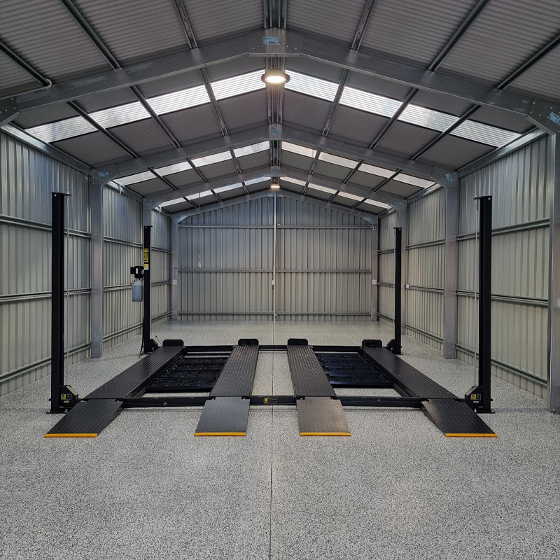 four-post car hoist with drive-on ramps and twin platforms installed in a spacious, well-lit metal garage, designed for efficient vehicle maintenance and storage. - 4 Post Twin Platform Parking Hoist – 4 Ton | TLD4.0TPL5.0M